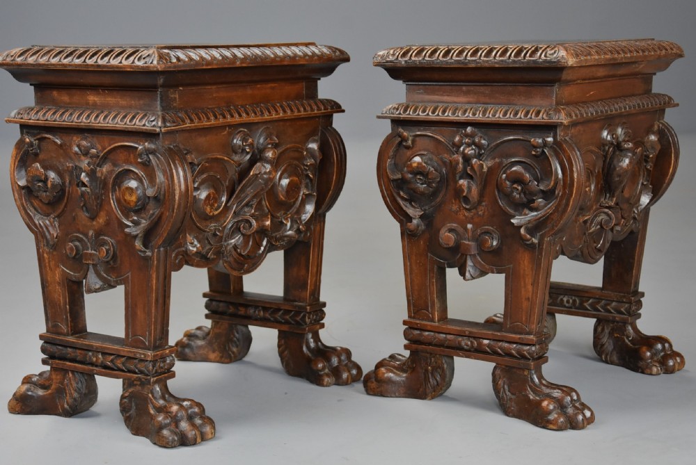 A pair of carved warm brown walnut stools with gadrooned tops, central bird reliefs, scrollwork aprons, and paw feet. View VI