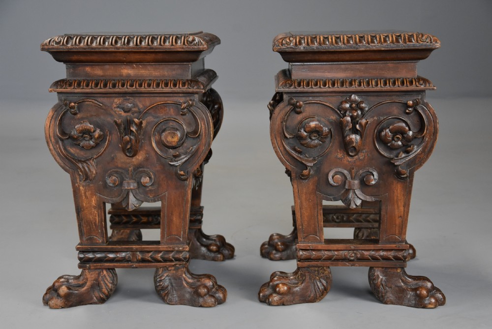 A pair of carved warm brown walnut stools with gadrooned tops, central bird reliefs, scrollwork aprons, and paw feet. View VIII
