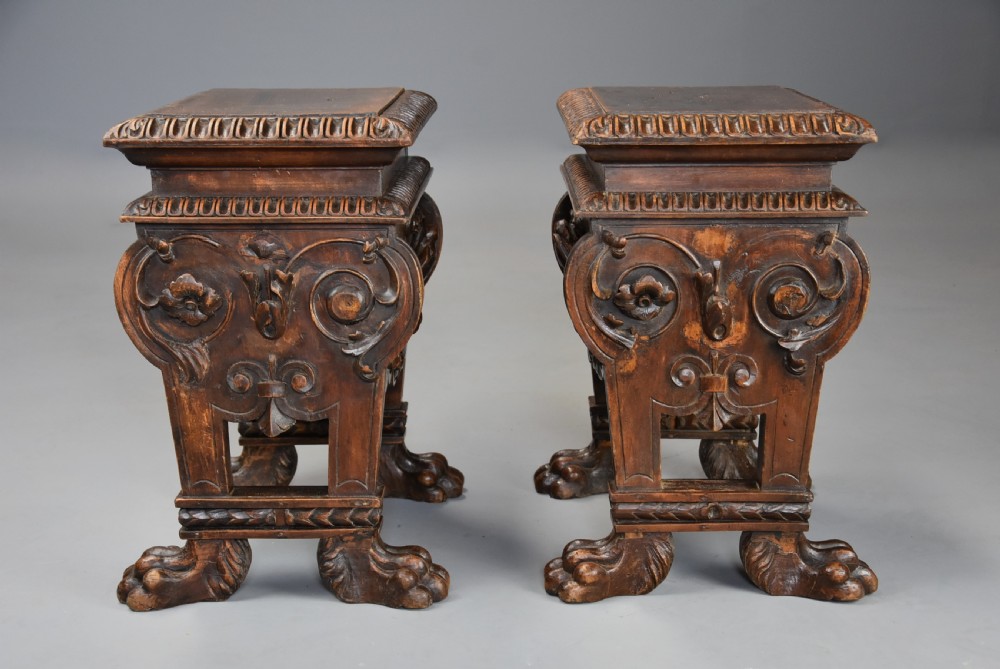 A pair of carved warm brown walnut stools with gadrooned tops, central bird reliefs, scrollwork aprons, and paw feet. View IX