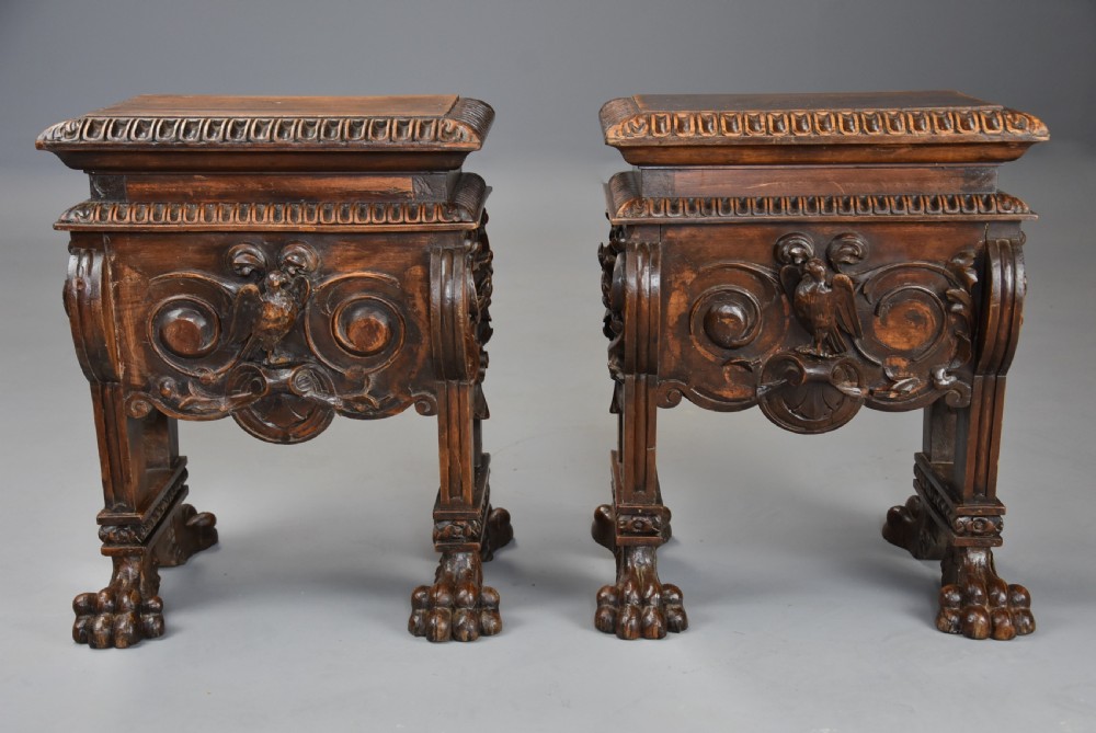 A pair of carved warm brown walnut stools with gadrooned tops, central bird reliefs, scrollwork aprons, and paw feet. View X