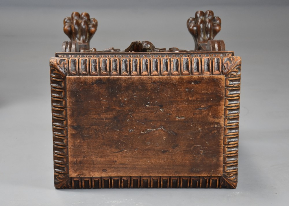 A pair of carved warm brown walnut stools with gadrooned tops, central bird reliefs, scrollwork aprons, and paw feet. View XII