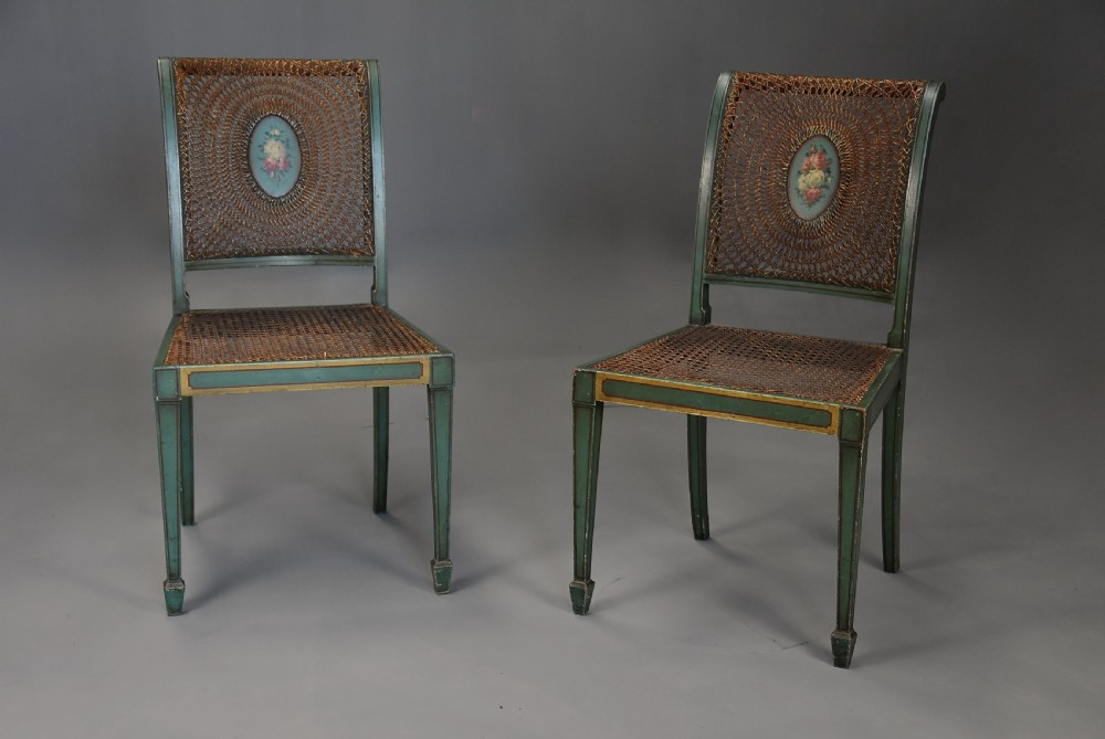 An early twentieth-century hand-painted green and gold bedroom suite featuring a wardrobe, chest of drawers with mirror, dressing desk, side tables, and caned chairs decorated with floral urn motifs. View XVIII
