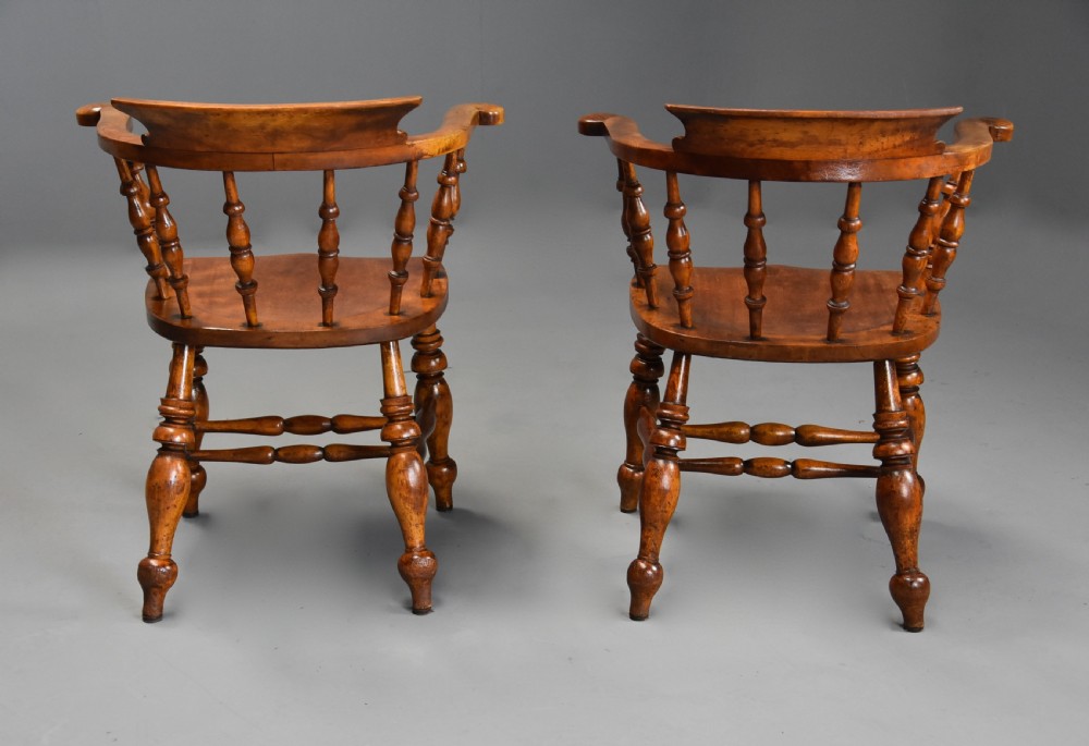 A pair of 19th-century birch smokers bow Windsor armchairs featuring steam-bent armrails, turned spindles, saddle seats, and turned legs with stretchers. View X