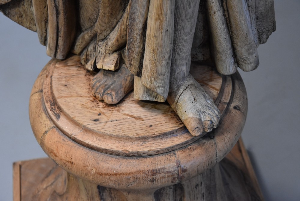 An 18th-century Continental carved oak figure depicting classical drapery standing on a turned pedestal. View IX