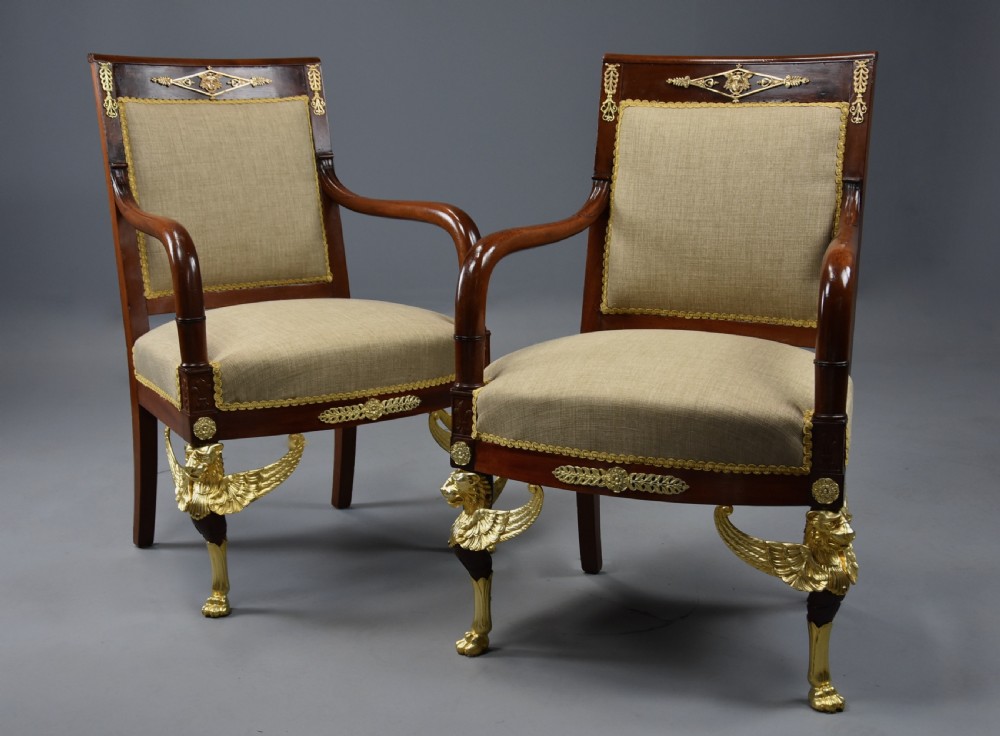 A pair of late nineteenth-century French mahogany open armchairs featuring gilded winged lion front legs and neutral fabric upholstery. View IV