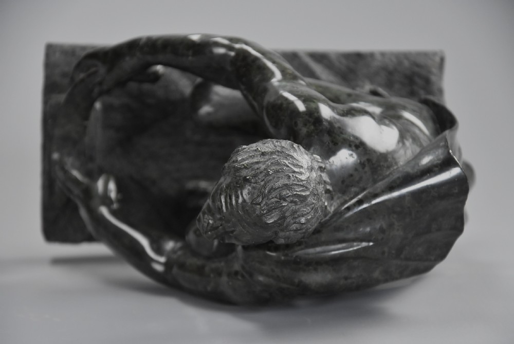 A dark green carved marble sculpture of the classical crouching figure Arrotino mounted on a rectangular plinth. View XI