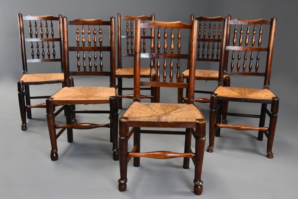 A set of six early nineteenth-century ash and elm spindle back dining chairs featuring woven rush seats and turned wooden stretchers. View III