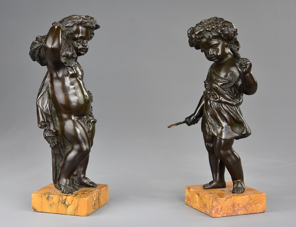 A pair of dark brown patinated bronze figures of harvest putti mounted on rectangular yellow veined marble bases. View II