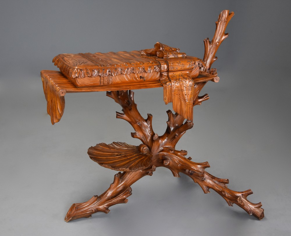 A late nineteenth-century Italian carved pine grotto work table featuring tree-branch legs, a shell shelf, and a top detailed as a cushion with draped cloth.