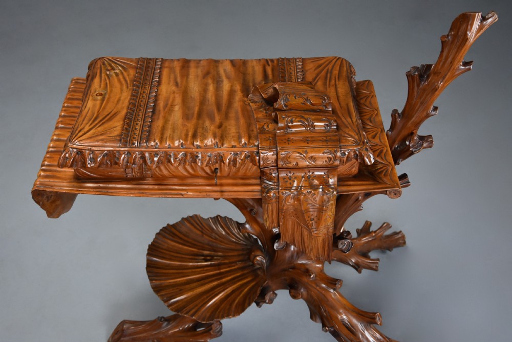 A late nineteenth-century Italian carved pine grotto work table featuring tree-branch legs, a shell shelf, and a top detailed as a cushion with draped cloth. View VI