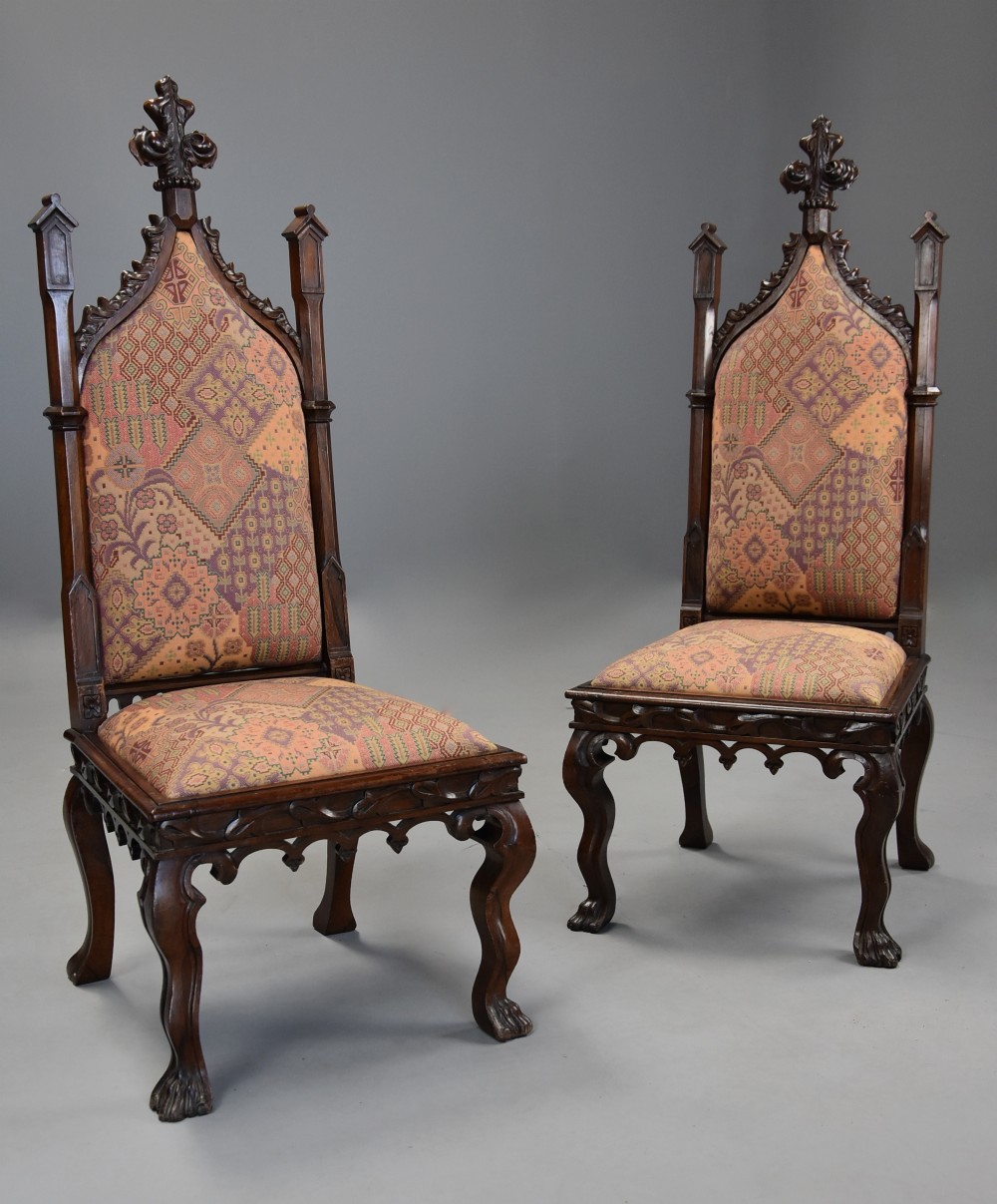 A pair of 19th-century rosewood Gothic Revival hall chairs featuring high pointed-arch backs with carved finials and patterned fabric upholstery.