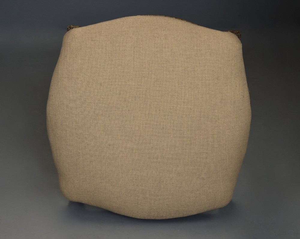 A mid-19th-century French carved giltwood footstool with a padded neutral linen seat, floral carving, and sweeping cabriole legs ending in scroll feet. View X