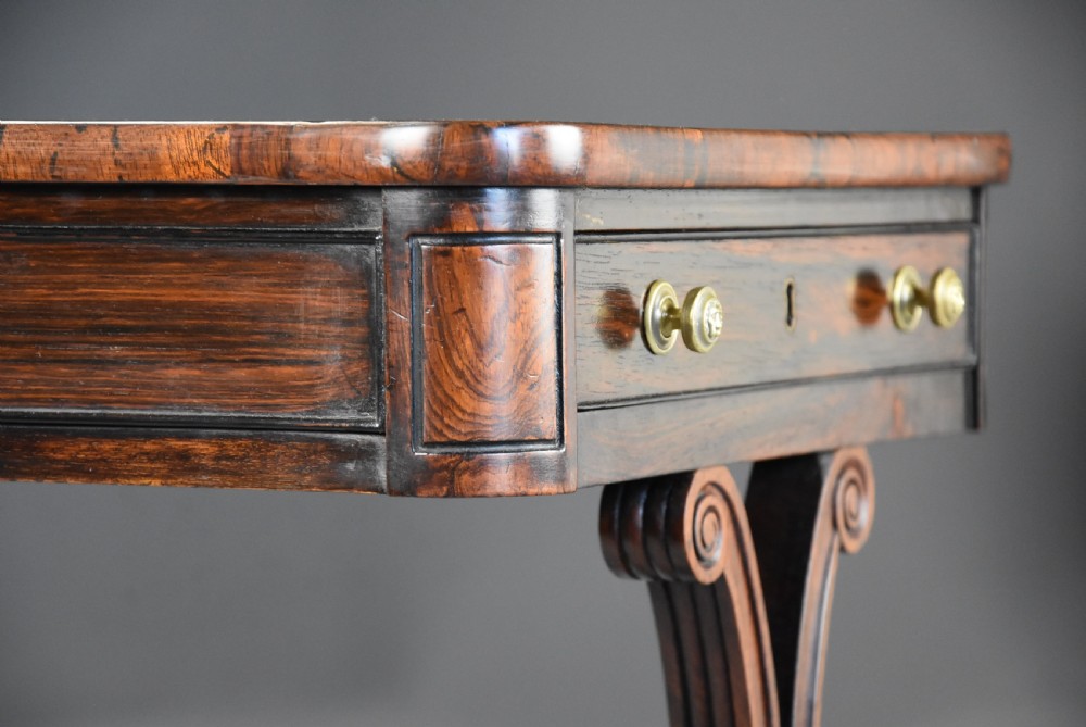 An early nineteenth-century rosewood occasional table featuring a rectangular top with a single drawer, scrolled trestle supports, beaded mouldings, and brass castors. View XI