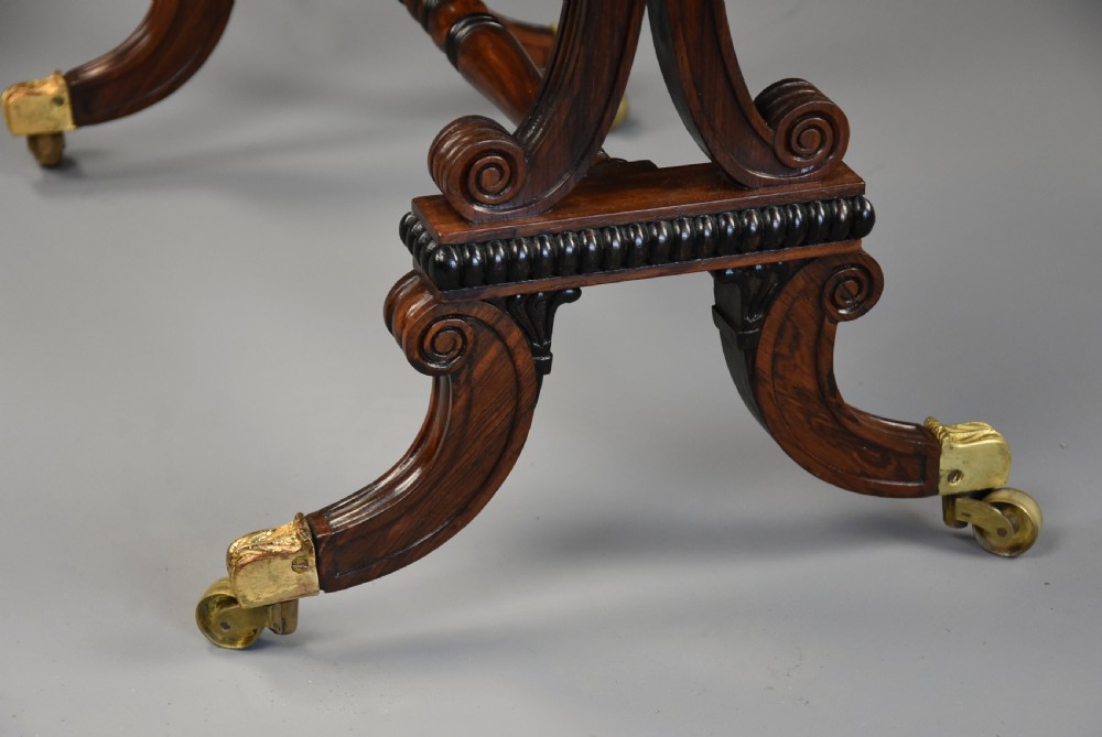 An early nineteenth-century rosewood occasional table featuring a rectangular top with a single drawer, scrolled trestle supports, beaded mouldings, and brass castors. View XV