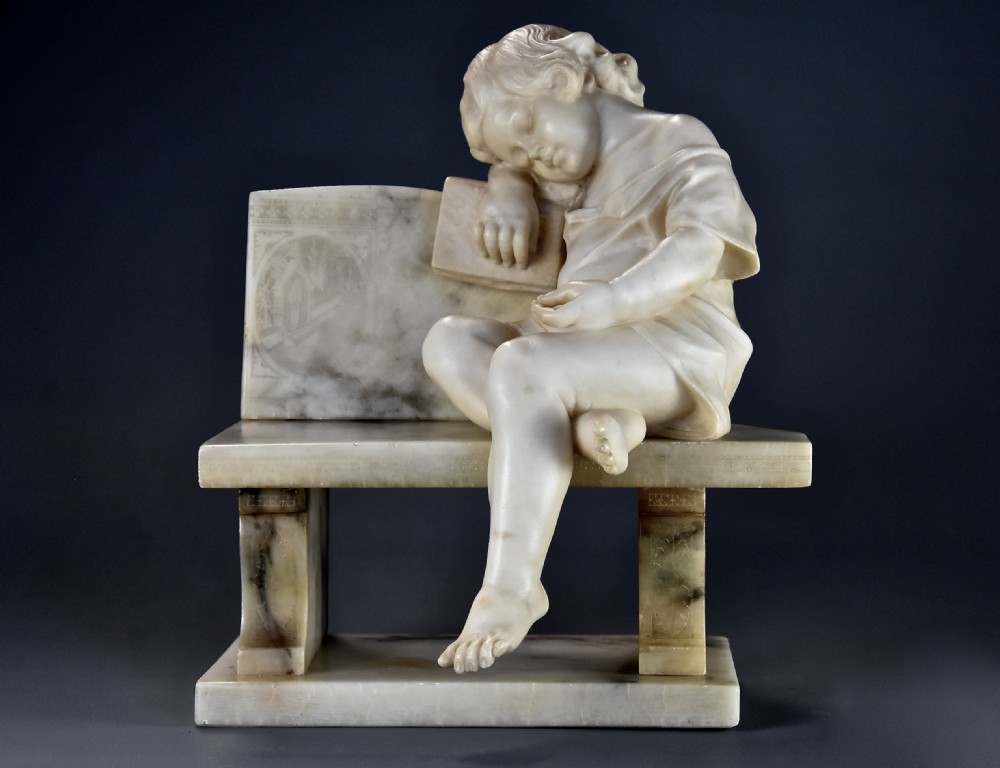 A late 19th-century carved alabaster sculpture depicting a sleeping child seated on a bench and resting against a book.