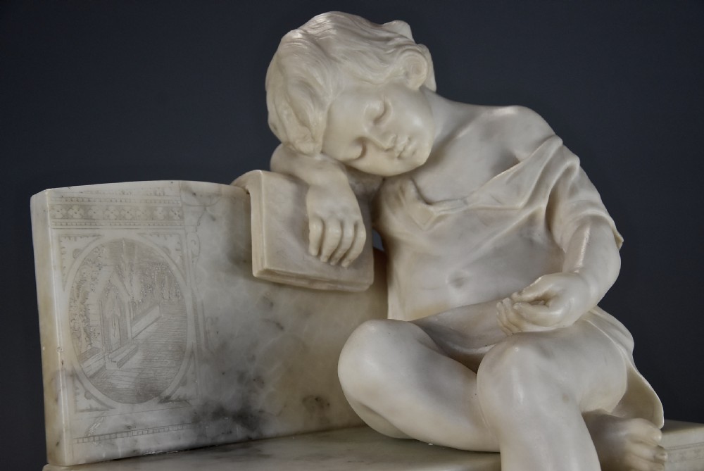 A late 19th-century carved alabaster sculpture depicting a sleeping child seated on a bench and resting against a book. View V