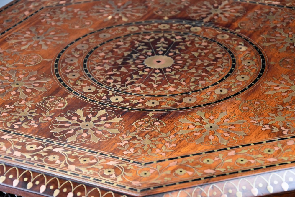 A late nineteenth-century Anglo-Indian octagonal table crafted from dark wood with intricate floral bone inlay on top and carved fretwork panels along the base. View IV