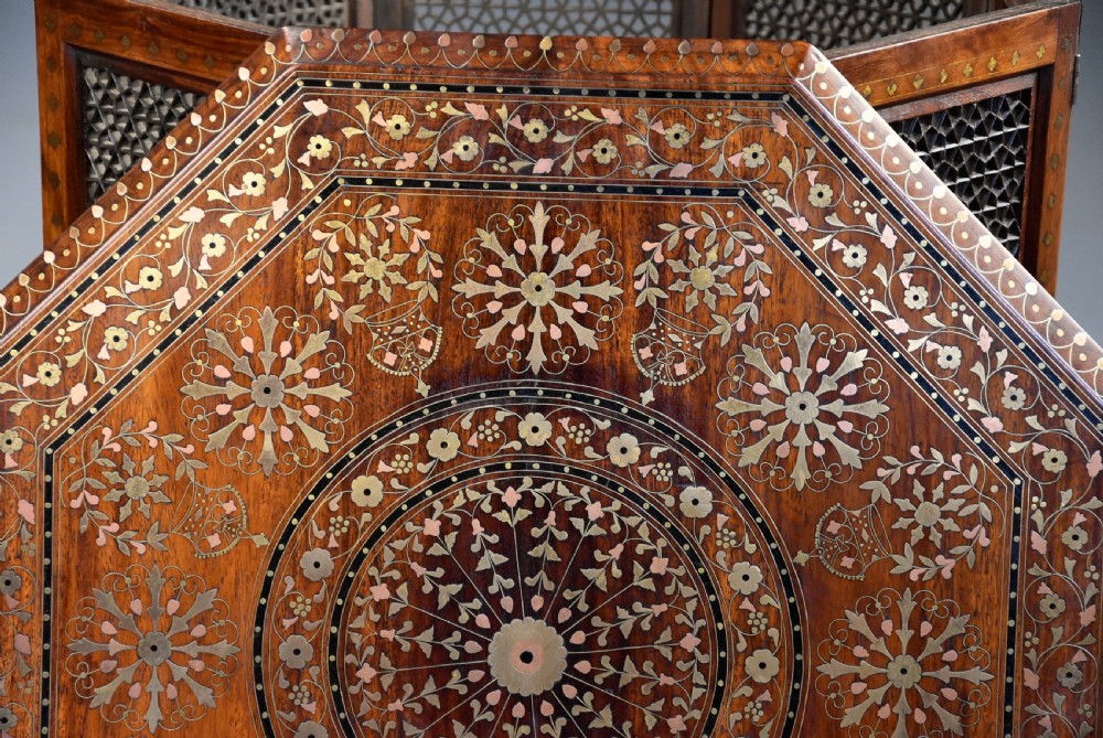 A late nineteenth-century Anglo-Indian octagonal table crafted from dark wood with intricate floral bone inlay on top and carved fretwork panels along the base. View VI