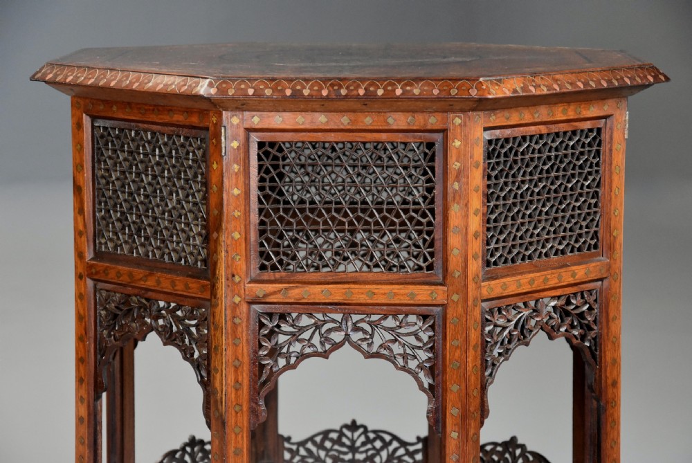 A late nineteenth-century Anglo-Indian octagonal table crafted from dark wood with intricate floral bone inlay on top and carved fretwork panels along the base. View IX
