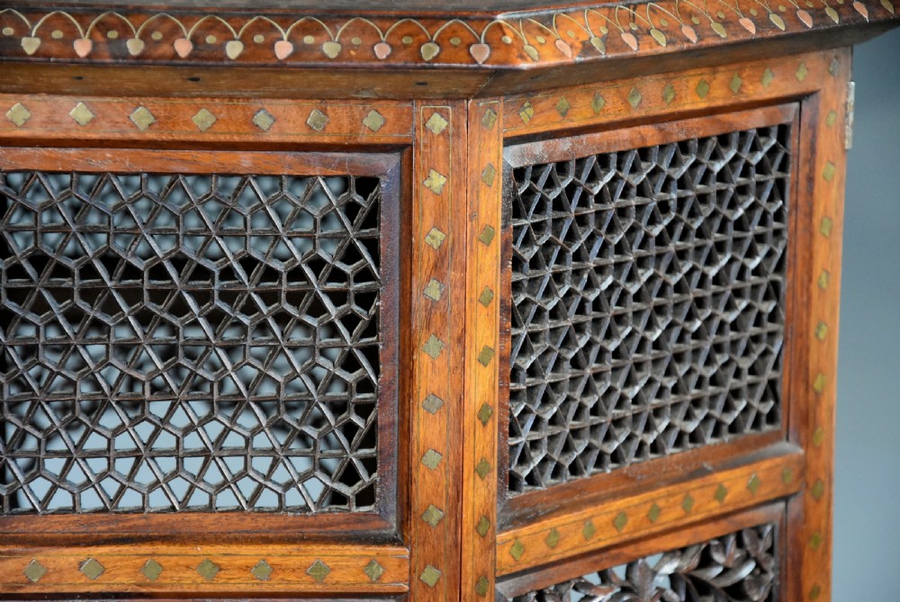 A late nineteenth-century Anglo-Indian octagonal table crafted from dark wood with intricate floral bone inlay on top and carved fretwork panels along the base. View X