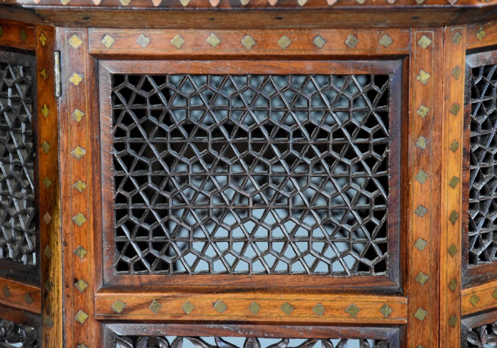 A late nineteenth-century Anglo-Indian octagonal table crafted from dark wood with intricate floral bone inlay on top and carved fretwork panels along the base. View XI