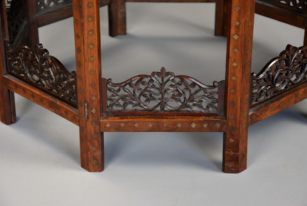 A late nineteenth-century Anglo-Indian octagonal table crafted from dark wood with intricate floral bone inlay on top and carved fretwork panels along the base. View XII