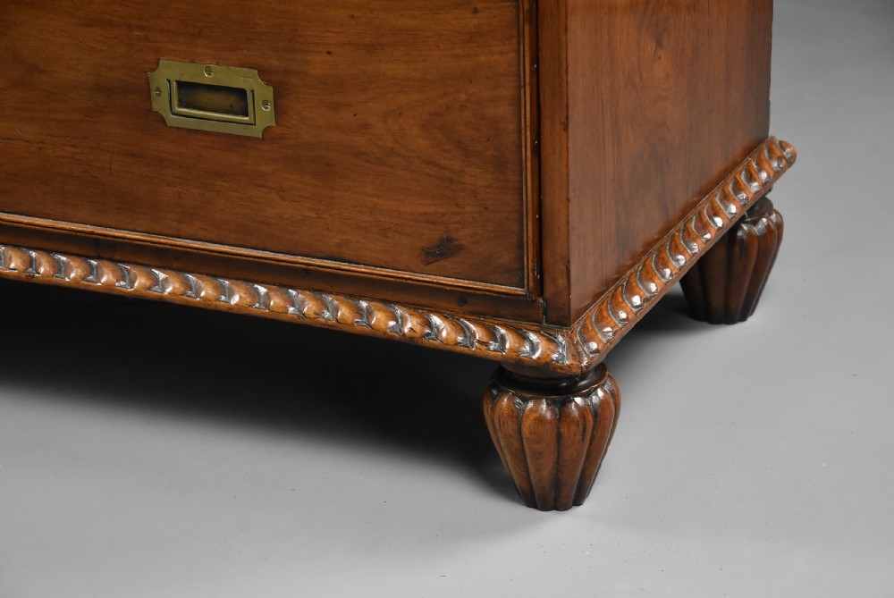 A late nineteenth-century padouk military chest of drawers featuring flush brass handles, carved rope-twist borders, and short fluted legs. View VI