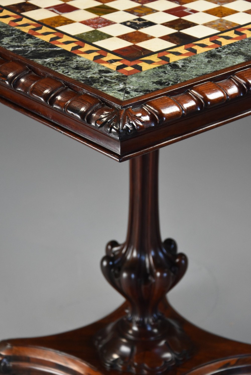 A mid-19th century rosewood games table featuring a square specimen marble inlaid chessboard top resting on a carved pedestal stem and scroll feet. View II