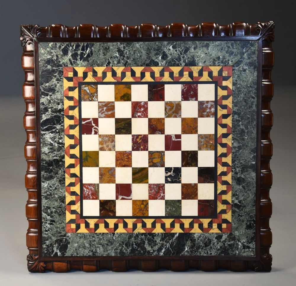 A mid-19th century rosewood games table featuring a square specimen marble inlaid chessboard top resting on a carved pedestal stem and scroll feet. View IV