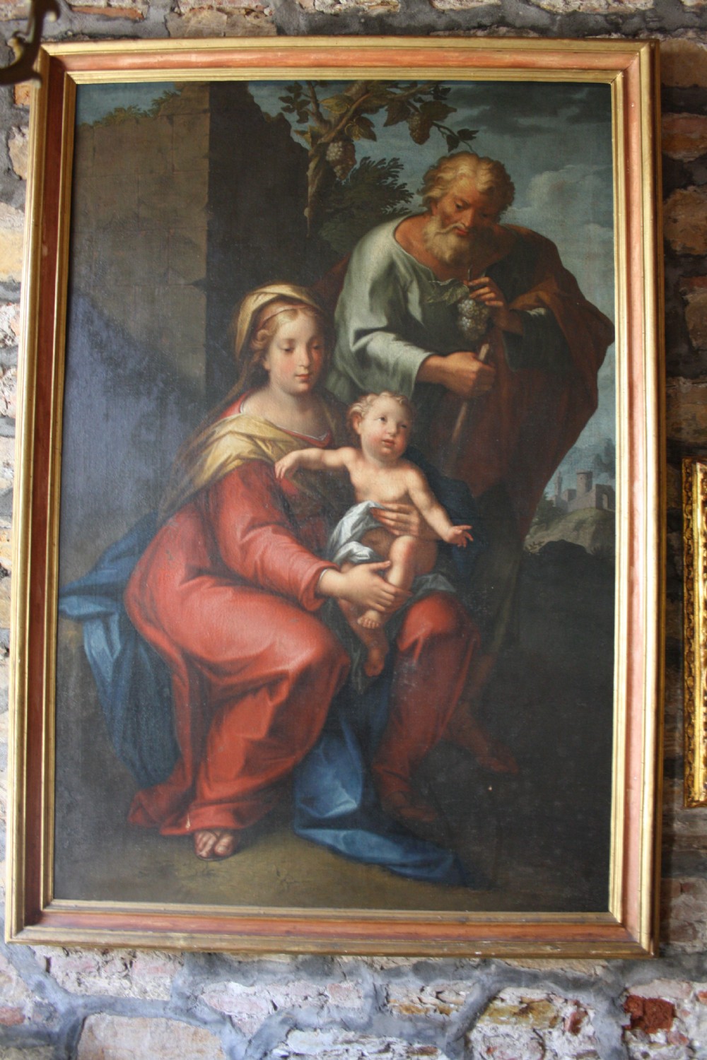 An 18th-century oil painting on canvas depicting the Holy Family set in a narrow gilded wooden frame.