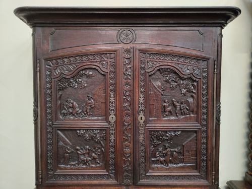fig 2. An antique dark oak French Provincial dresser featuring intricate relief carvings of figurative village scenes on four cupboard doors and three drawers.
