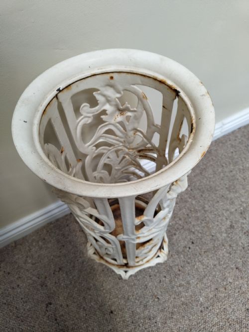 fig 1. An antique white-painted cast iron cylindrical umbrella stand featuring ornate openwork foliate scrolls and a circular drip pan base.