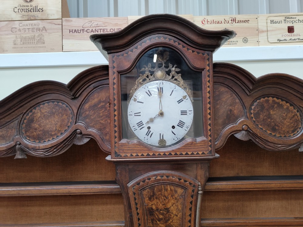A carved oak French provincial clock dresser featuring an integrated central longcase clock, open shelving, and a lower sideboard with drawers and cupboards. View VII