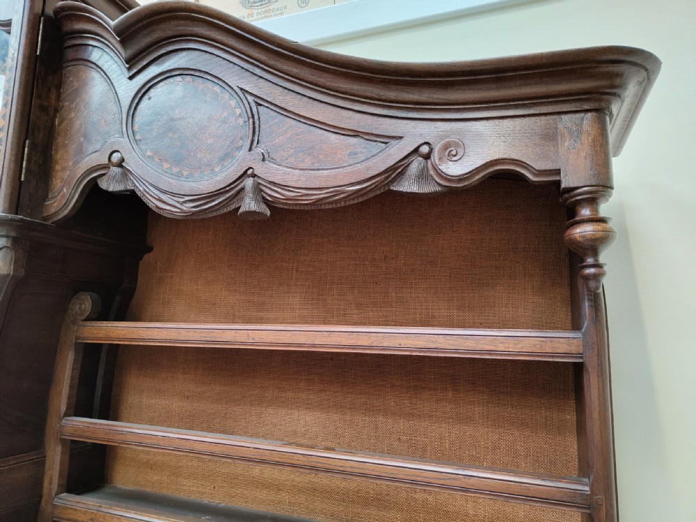 A carved oak French provincial clock dresser featuring an integrated central longcase clock, open shelving, and a lower sideboard with drawers and cupboards. View VIII