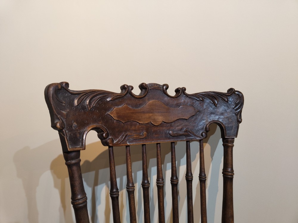 A pair of matching dark brown wooden rocking chairs featuring carved crest rails, spindle backrests, shaped wooden seats, and turned legs on curved runners. View V