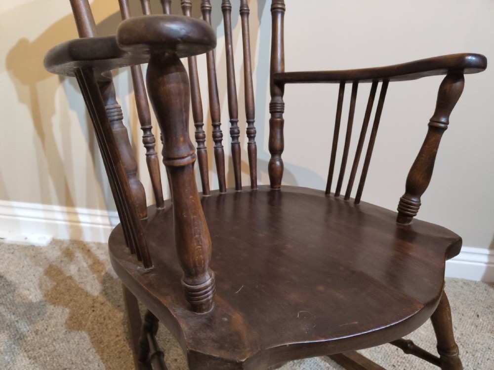 A pair of matching dark brown wooden rocking chairs featuring carved crest rails, spindle backrests, shaped wooden seats, and turned legs on curved runners. View VI
