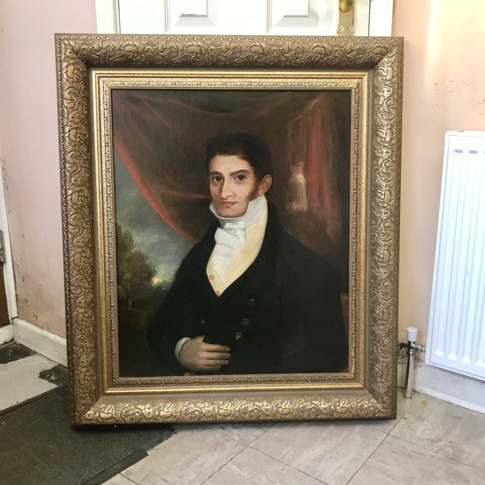 An antique oil painting depicting a Regency gentleman in a dark coat and white cravat, set within an ornate, carved gold frame. View II