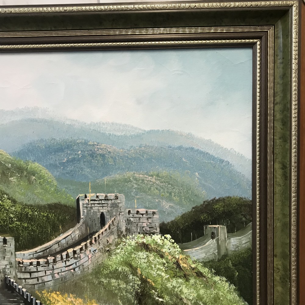 A large horizontal oil painting depicting the Great Wall of China winding through lush green mountains under a cloudy sky, encased in a metallic green and gold frame. View XV
