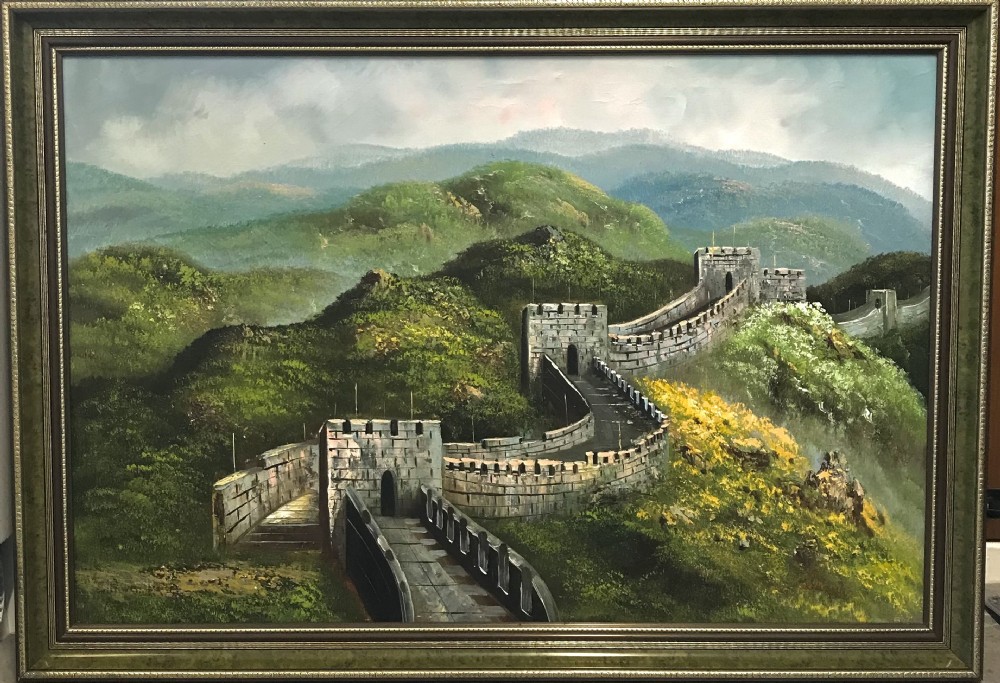 A large horizontal oil painting depicting the Great Wall of China winding through lush green mountains under a cloudy sky, encased in a metallic green and gold frame.