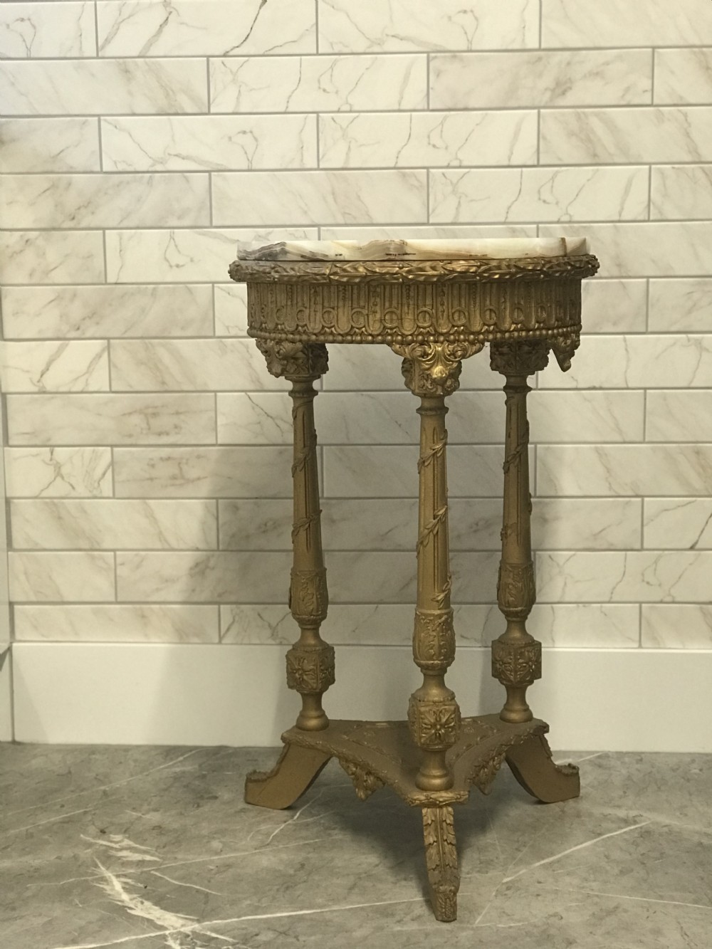 A 19th-century French round table featuring a variegated onyx top, a gilt frieze with decorative mouldings, and three carved column supports above a triangular base. View XXXI