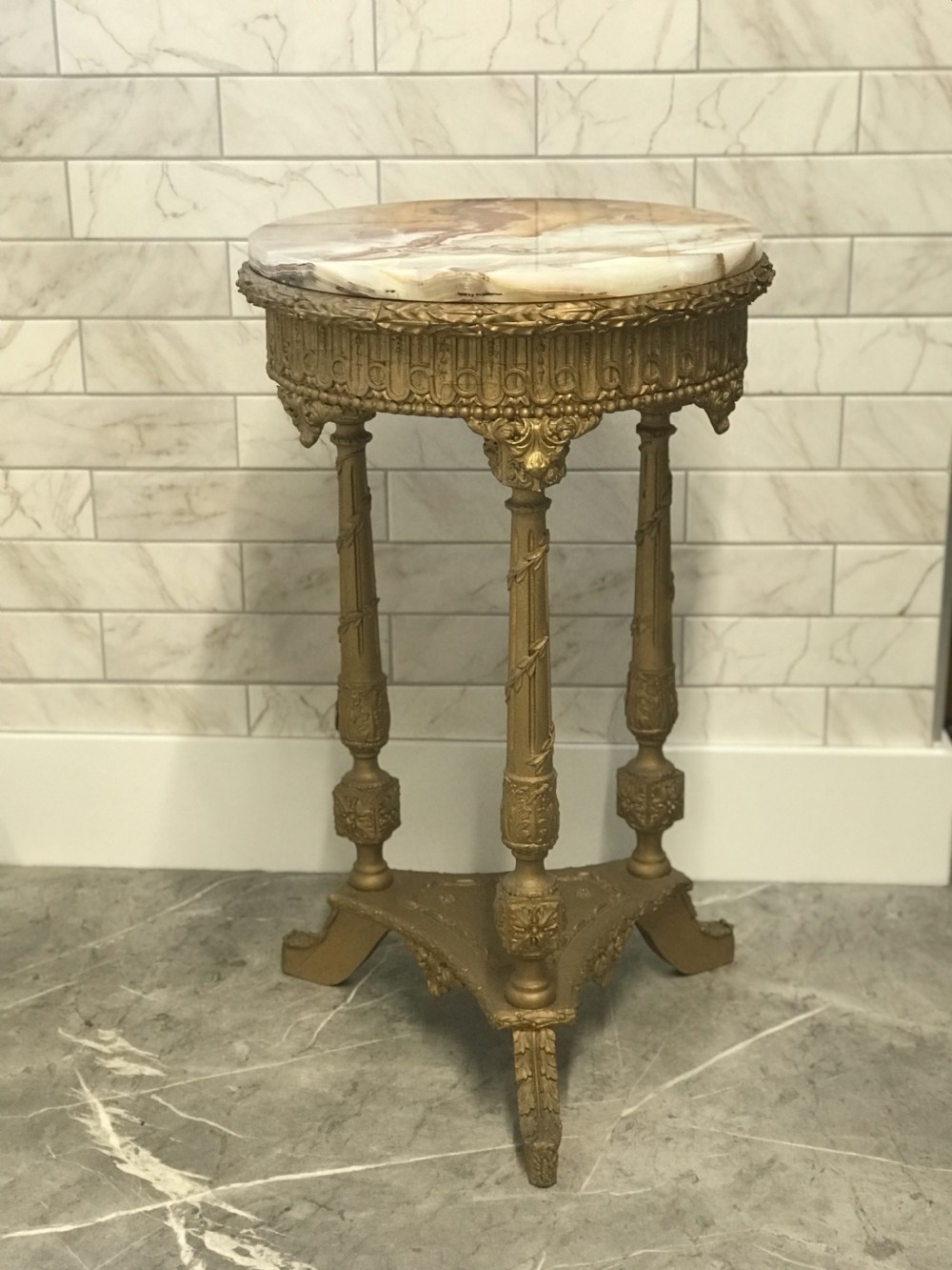 A 19th-century French round table featuring a variegated onyx top, a gilt frieze with decorative mouldings, and three carved column supports above a triangular base. View XXV