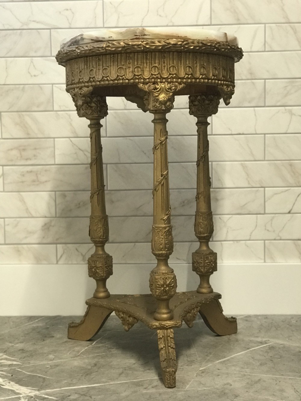 A 19th-century French round table featuring a variegated onyx top, a gilt frieze with decorative mouldings, and three carved column supports above a triangular base. View XII