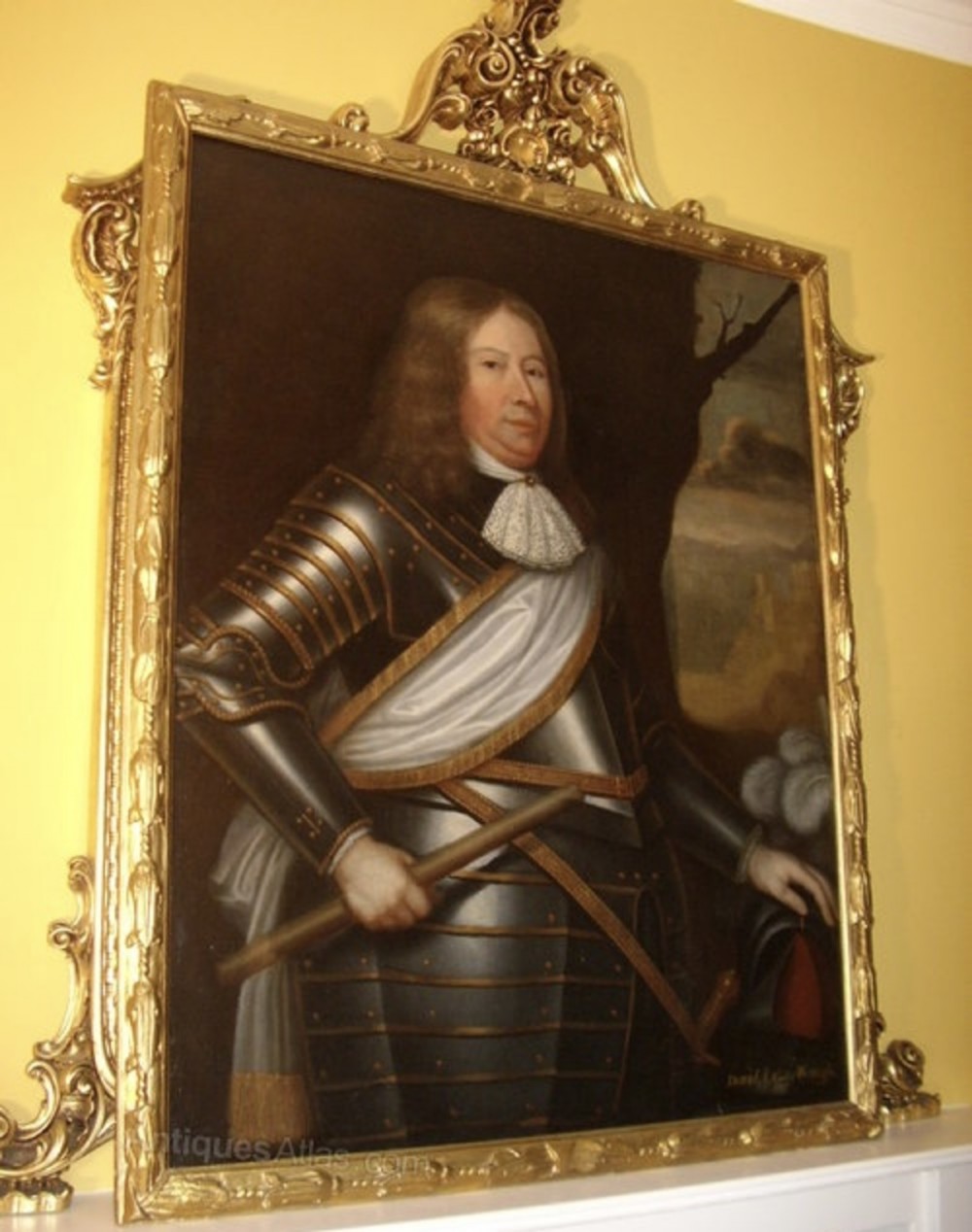 A seventeenth-century oil painting portraying a gentleman in plate armour with a lace cravat, set within an ornate gilded frame.