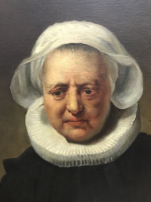 An 18th-century oil portrait of an elderly woman wearing a white bonnet and ruff collar, set inside an oval spandrel within a rectangular gilded frame. View III