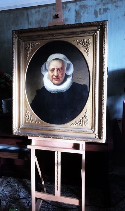 An 18th-century oil portrait of an elderly woman wearing a white bonnet and ruff collar, set inside an oval spandrel within a rectangular gilded frame. View IX