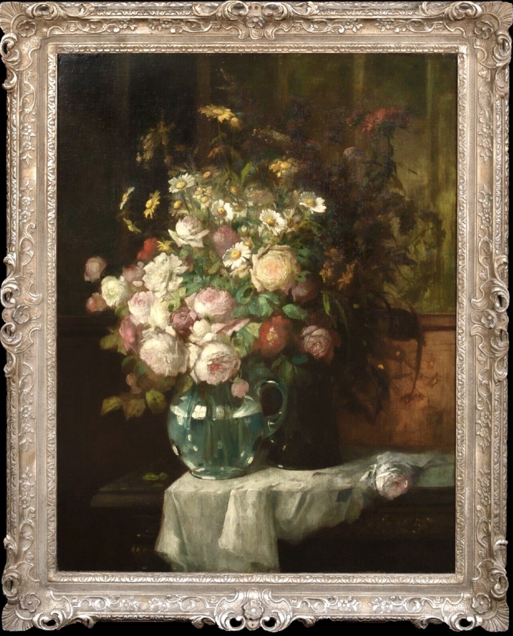 A 19th-century oil painting on canvas featuring a prominent vase of white and pink flowers on a draped tablecloth, set within an ornate silvered carved frame.