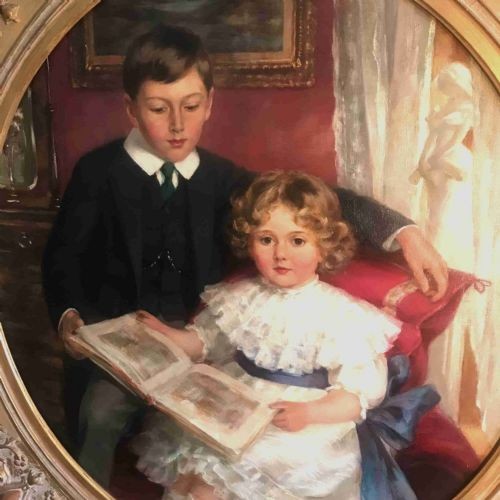 An Edwardian oil portrait painting depicting a young boy and girl reading a book together, presented within a square gilt frame featuring an oval aperture. View IV