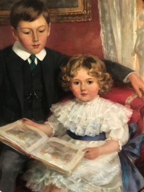 An Edwardian oil portrait painting depicting a young boy and girl reading a book together, presented within a square gilt frame featuring an oval aperture. View VII