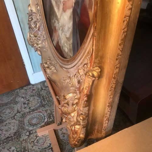 An Edwardian oil portrait painting depicting a young boy and girl reading a book together, presented within a square gilt frame featuring an oval aperture. View X