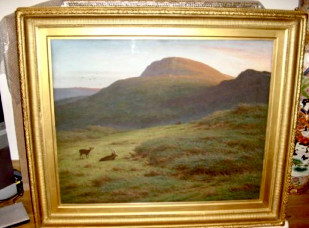 A large framed landscape painting depicting rolling green hills and deer under a muted sky within a moulded gold gilt frame.